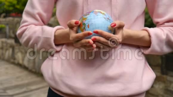 年轻的女青少年红色指甲和粉红色毛衣给一个小地球与地理上的名字在乌克兰视频的预览图