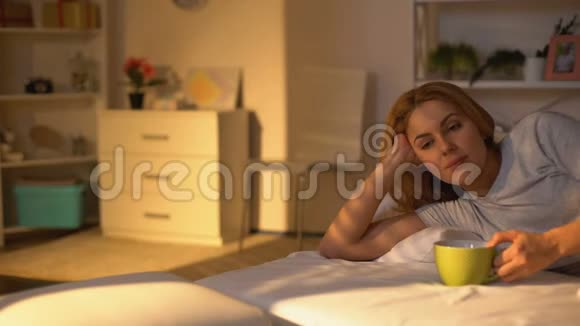 放松的快乐女人躺在床上喝咖啡周末早上休息和平视频的预览图