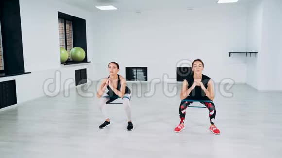 女孩做有弹性的蹲可爱的性感女孩在健身房做运动使用弹性视频的预览图