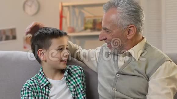 爷爷抚摸孙子的头拥抱和看着相机家庭时间视频的预览图