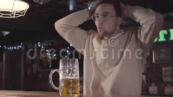 迷人的年轻人开心地笑着在酒吧喝啤酒看电视上的足球比赛它的风扇视频的预览图