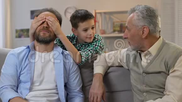 儿子闭上父亲的眼睛祖父送礼物盒生日惊喜家人视频的预览图