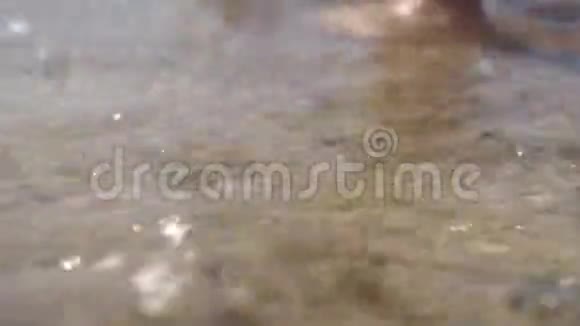 孩子的脚赤脚走在岸边一个被海浪抛起的黑色浮球视频的预览图