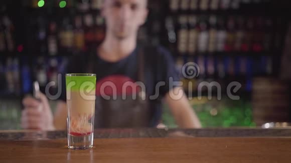 在一个模糊的年轻酒吧老板的背景下在酒吧或餐馆的酒吧柜台前为鸡尾酒做特写视频的预览图