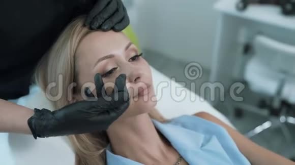 特写美容医生双手在病人面部上显示美容手术用的面部区域Stealicam镜头视频的预览图