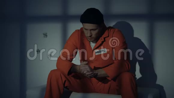不高兴的白种人男性囚犯对犯罪感到内疚在牢房里思考视频的预览图