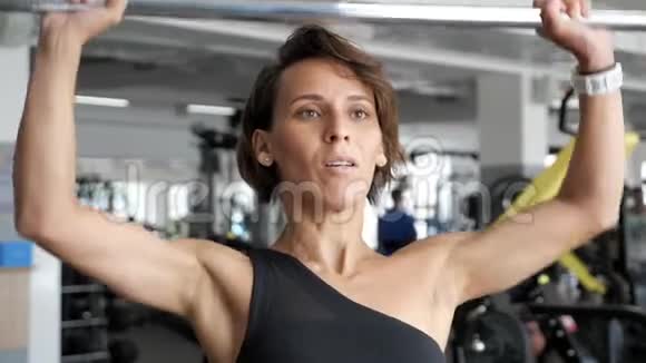 女人正在做一套代表运动杠铃在健身房把它举过头顶视频的预览图