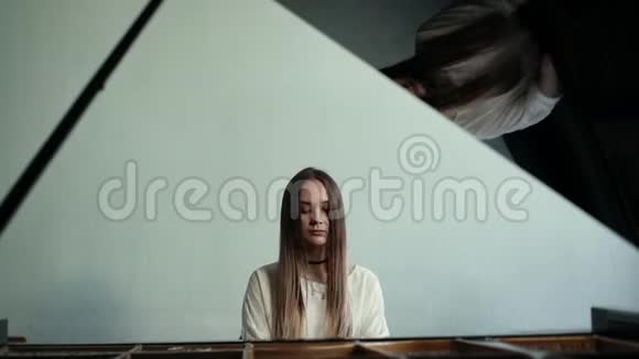 女钢琴家在墙上慢动作的背景下弹奏钢琴音乐视频的预览图