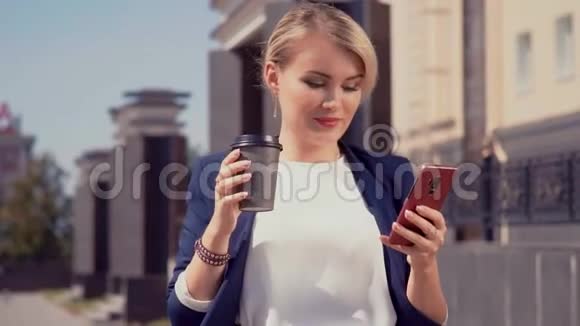 一只手拿着咖啡杯另一只手拿着电话走在街上的白人女孩在看书视频的预览图