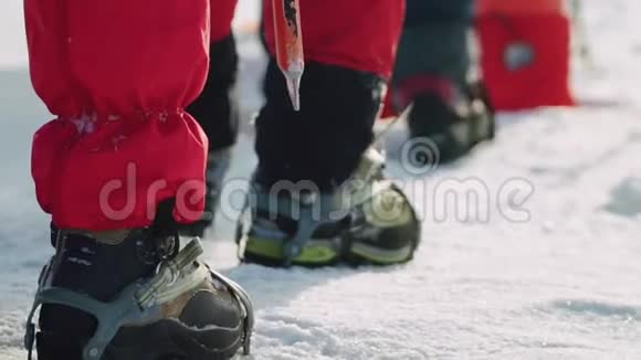 穿着雪鞋在厚厚的雪地上行走的登山者的脚团队沿着一条路走在一起帮助视频的预览图