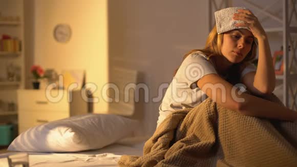 患偏头痛的女士额头上有毛巾躺在家里的床上视频的预览图