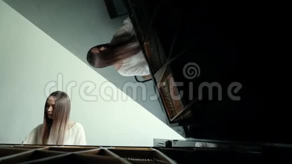 女钢琴家在墙上慢动作的背景下弹奏钢琴音乐视频的预览图