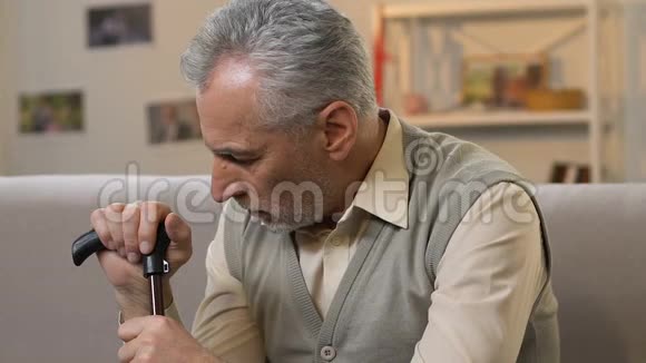 伤心的老人拿着拐杖坐在家里看着摄像机孤独视频的预览图