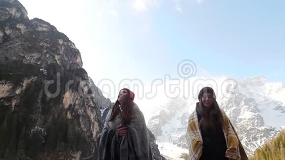 两个年轻的女人被覆盖在毯子里走在冰冻的湖面上视频的预览图