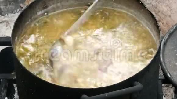 美丽美味的汤在火上的大锅里沸腾营地厨房一只手拿着一个钢包混合了配料纳特烹饪视频的预览图