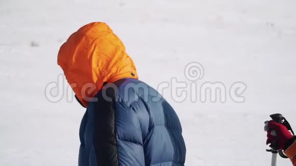 登山者戴着特殊的帽子温暖的夹克和运动眼镜在雪地里缓慢而自信地前行视频的预览图