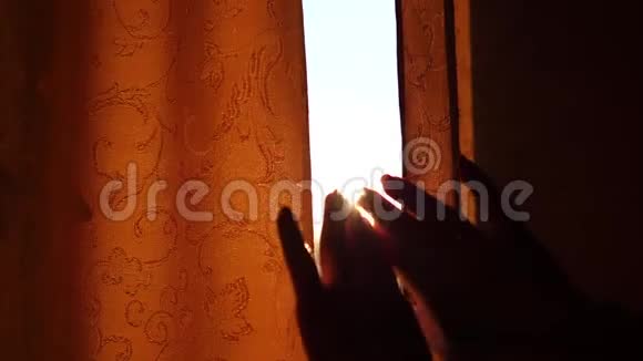 那个女孩在清晨拉开窗帘太阳光线穿过窗户和手指视频的预览图