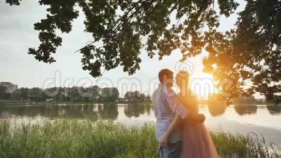 日落时一对年轻夫妇站在湖边视频的预览图