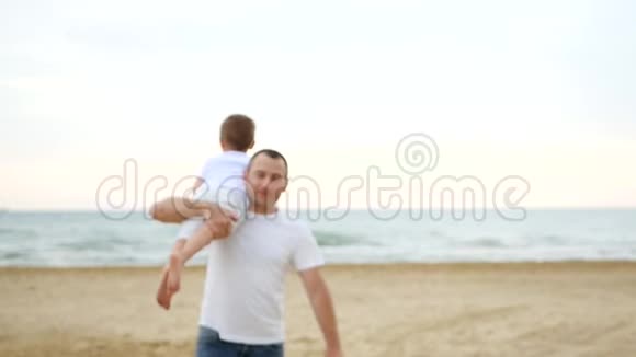 一个男人带着一个孩子在沙滩上慢慢地走着视频的预览图