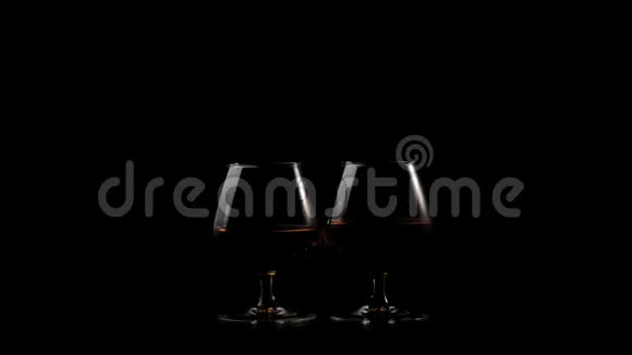 豪华白兰地两杯金色干邑黑色背景的黑桌上光线照在桌子上玻璃视频的预览图