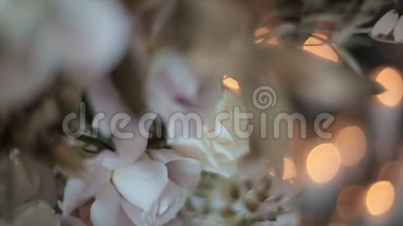 玫瑰花装饰在模糊的背景上从灯光的眩光从燃烧的蜡烛优雅的晚间装饰视频的预览图