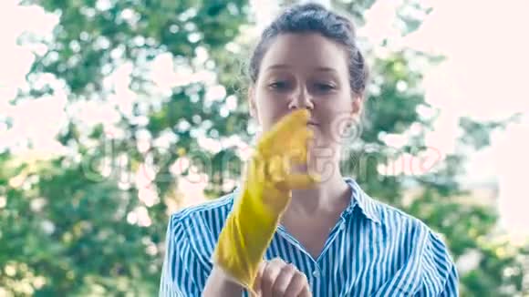 穿蓝色白衬衫的漂亮女士戴着黄色橡胶手套视频的预览图