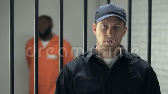 监狱长看着摄像机站在牢房附近被监禁的美国黑人视频的预览图