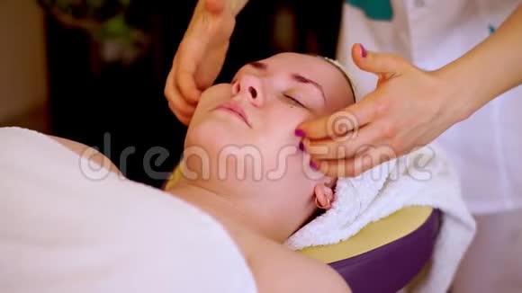 做圆周运动的美容师的手可以按摩脸颊眉毛和额头客户躺在床上放松视频的预览图