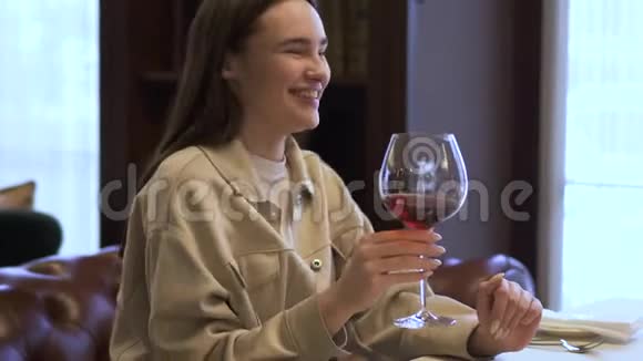 美丽的女孩留着长发在餐厅休息女士在微笑女士在一杯红酒中视频的预览图