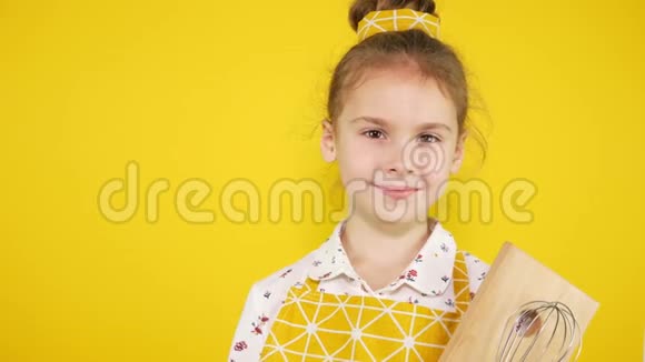 黄色背景带厨房用具的黄色围裙的厨师女孩视频的预览图