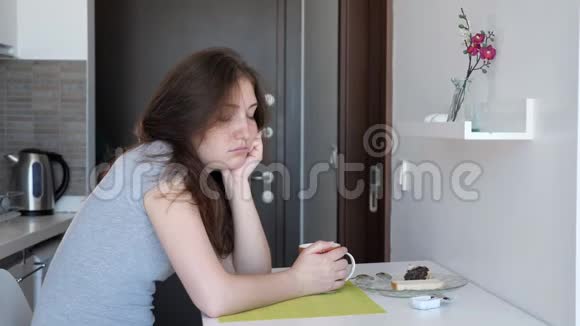 睡眠不足的女人正坐在小厨房里在度假时租公寓喝茶视频的预览图