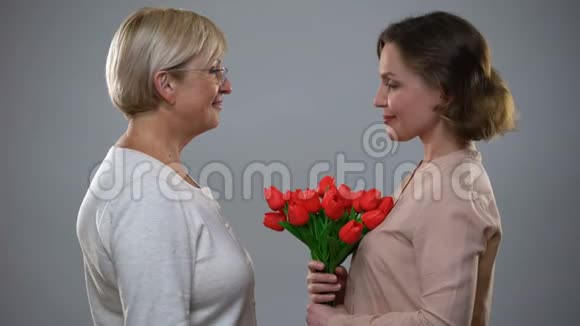 可爱的女儿把红色郁金香送给成熟的母亲国际妇女节视频的预览图