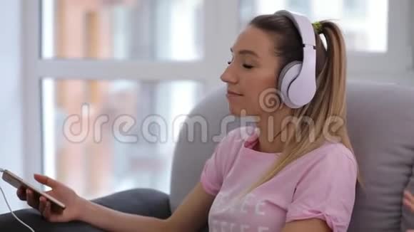 女人在家放松喝杯茶戴上耳机听音乐视频的预览图