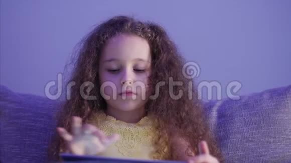 一个高加索可爱的孩子一个小女孩特写一个孩子的夜景一台平板电脑视频的预览图