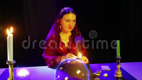 一个在魔法沙龙里的吉普赛人用水晶球进行魔法从水晶球里发出电光和点燃蜡烛视频的预览图