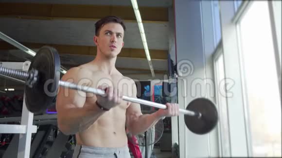 年轻健美运动员提杠铃做二头肌运动视频的预览图