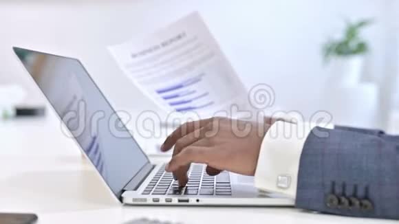 关闭非洲男子阅读文件的手并在笔记本电脑上工作视频的预览图