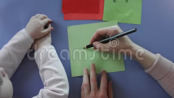 合上母女双手握着铅笔在纸上画着微笑在家一起玩耍孩子和母亲视频的预览图