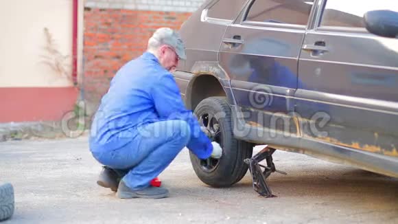 一名男性汽车修理工将汽车降低到地面并将车轮固定在汽车的车轴上时光飞逝视频的预览图