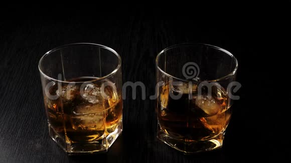 豪华威士忌手拿着一杯金色威士忌和真正的冷冰从黑桌上不倒翁威士忌波旁酒视频的预览图