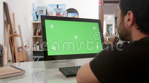 一个蓄胡子的男人看着电脑上的绿色屏幕视频的预览图
