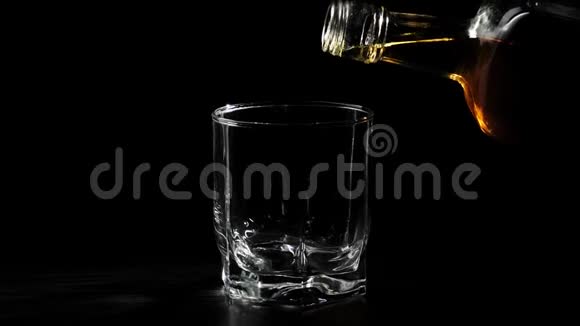 豪华威士忌手把金色的威士忌从一个方形的瓶子里倒入旋转的黑色桌子上的玻璃杯里不倒翁威士忌波旁视频的预览图