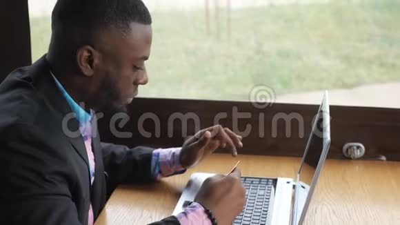 黑人在笔记本电脑上做支付银行卡在线购买在咖啡馆购物视频的预览图