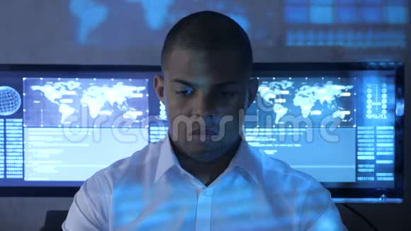 美国黑人男程序员穿着白色衬衫在安全数据中心的计算机上工作的肖像全息编码视频的预览图