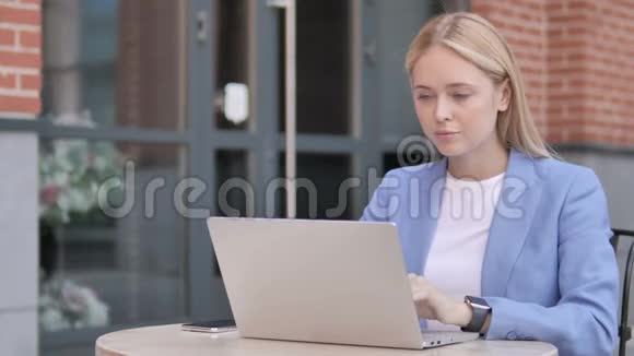 颈部疼痛的年轻女商人使用笔记本电脑户外视频的预览图
