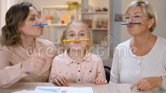有趣的多代女性拿着彩色铅笔在鼻子和嘴唇之间游戏视频的预览图