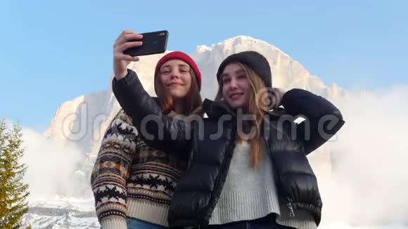 两个年轻的微笑女人站在一座山的背景上自拍视频的预览图