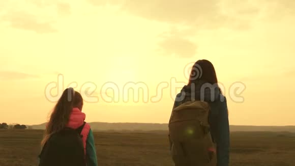 妈妈和女儿在日落时带着背包旅行女孩们在远足游客母亲和孩子去日落视频的预览图