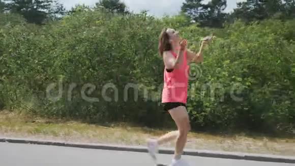 漂亮的女孩有着有趣的棕色活泼的年轻女子在公园跳舞布鲁内特女孩在公园里玩得很开心穿粉色衬衫的女人视频的预览图