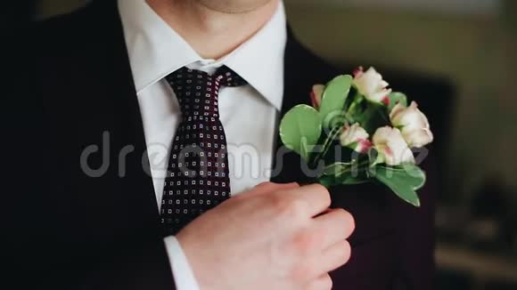那人把西装上的花束弄直了他的手和花束本身的特写视频的预览图